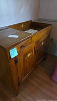 Side view of antique wooden washstand cabinet showing wood finish and original metal hardware.