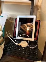 Apple iPad with black keyboard case and charger cable on keyboard