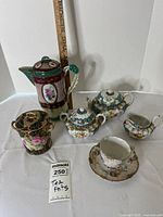 Full assortment of vintage porcelain tea set, showing all items on white surface with ruler for scale