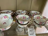 Set of 12 porcelain soup bowls with floral pattern and gold trim, stacked and displayed.