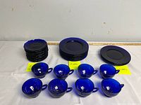 Full view of set showing 4 larger plates, 12 saucer plates and 8 teacups in cobalt blue glass.