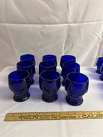 Front view of nine large cobalt blue tumblers arranged with a ruler for size reference showing approximately 3-inch height
