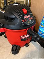 Front angle view of the Craftsman 16-gallon wet/dry vacuum with label showing 6.0 peak HP and 170 MPH blowing speed, hose attached.