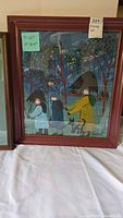 Folk art painting framed, showing three people and a dog in forest