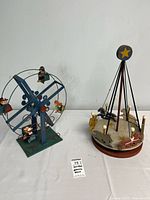Photo displaying a tin Ferris wheel music box on the left and a wooden carousel on the right, both vintage with minor paint wear.