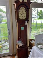 Full height front view of clock showing arched bonnet, front door, and wood finish