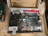 Box with many train tracks, train cars and accessories inside, arranged loosely