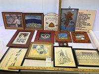 Photo showing multiple framed art prints and signage items arranged on a white surface, including landscapes, calligraphy, and typography prints.