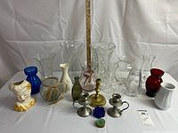 Full lot of various glass, ceramic, and metal vases and candle holders displayed on white background with measuring stick