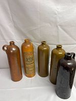 Set of five antique stoneware bottles in various colors and shapes, one with original label