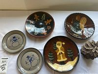 Top view of the five stoneware plates with Christmas and holiday designs including snowmen, gingerbread men, angel, and Santa.