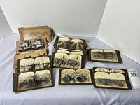 Group shot displaying multiple stacks of Underwood & Underwood stereoview cards, showing sepia and black-and-white images of military and historical scenes spread out on a white background.