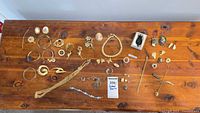 Overview of entire lot laid out on wood table, showing all necklaces, bracelets, brooches, earrings, rings and pins