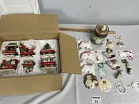 Photo of boxed Danbury Mint Westie Christmas Express ornaments and various other Westie-shaped Christmas and decorative ornaments, including figurines and hanging designs, all arranged on a tabletop.