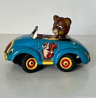 Side view showing blue tin car, bear driver, squirrel graphic, wheels