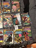 Nine comics arranged on bed, covers visible