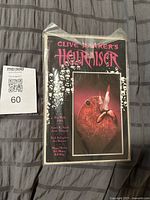 Front view of bagged Clive Barker’s Hellraiser comic with MaxSold lot card