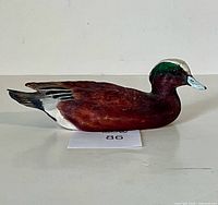 Left side profile of carved wooden duck decoy showing paint details
