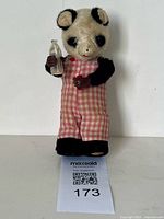 Front view of wind-up panda bear toy holding bottle