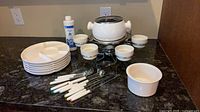 Full set laid out: fondue pot on stand, six ramekins, six forks, stainless spoons, stack of plates