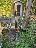 Fiskars lopper and hedge shear leaning against fence