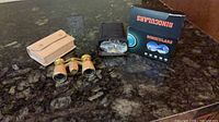 Opera glasses, beige case, compact binoculars soft case and box on countertop