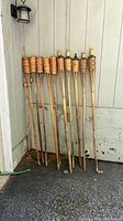 Full view of 10 bamboo tiki torches leaning against wall