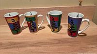 Four tall color-block Christmas latte mugs front view