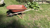 Full side view of red True Temper wheelbarrow resting on lawn