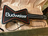 Front view of Budweiser guitar light-up sign with power cord visible