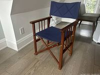 Front angled view of wood folding director chair with navy canvas seat/back