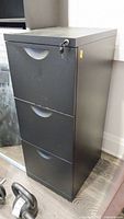 Front view of black three-drawer metal filing cabinet