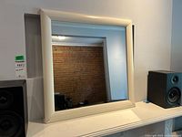 Front view of square white frame mirror on shelf