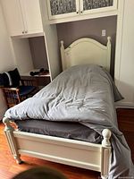 Full view of painted wood twin bed frame with mattress in alcove