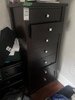 Front view of dark wood tallboy dresser with drawers closed
