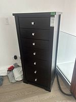 Front view of tall dark wood seven-drawer dresser with metal knobs