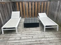 Two white resin lounge chairs on wooden deck