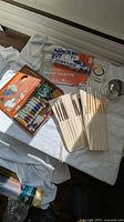 Overview of lot showing wooden paint box with paint tubes, brush roll, sealed paper palette pad, colour guide and metal tin