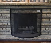 Front view of black metal fireplace screen against brick fireplace