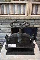 Front view of cast iron book press showing hand wheel and frame