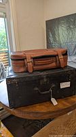Brown soft-side suitcase stacked on black hard-side suitcase