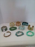 Ten assorted bracelets including various colors and materials laid out on flat surface with white background.