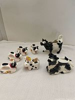 Photo showing all 7 items in the cow kitchen set including 4 napkin holders, toothpick holder, cream and sugar dispensers arranged on a white surface.