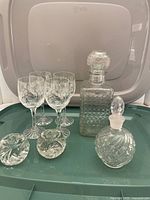 Full lot including 4 pinwheel patterned wine glasses, 2 glass decanters with stoppers, and 2 small glass candle holders displayed on a tray.