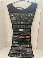 Umbra black jewelry holder open showing clear vinyl pockets with assorted jewelry inside held visibly
