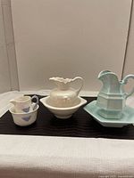 Group photo of three jug and dish sets showing variety of sizes and designs including blue and white ceramics and pale turquoise set