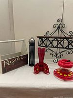 Wooden planter box, black metal bird seed feeder, two red hummingbird feeders, and hanging flower planter on white surface against white background