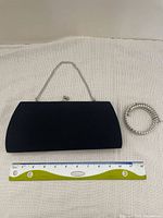 Photo showing the black clutch with silver chain and the faux pearl choker placed beside a ruler for size comparison.