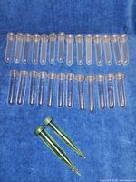 Full set of 26 clear and 2 green flower stem holders laid out on blue fabric background