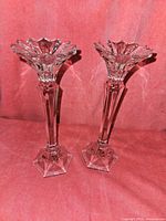 Front view of two crystal candle holders showing detailed faceted design and hexagonal bases on pink background